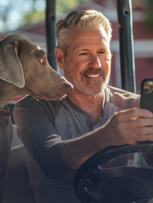 A man is looking at his phone with his dog